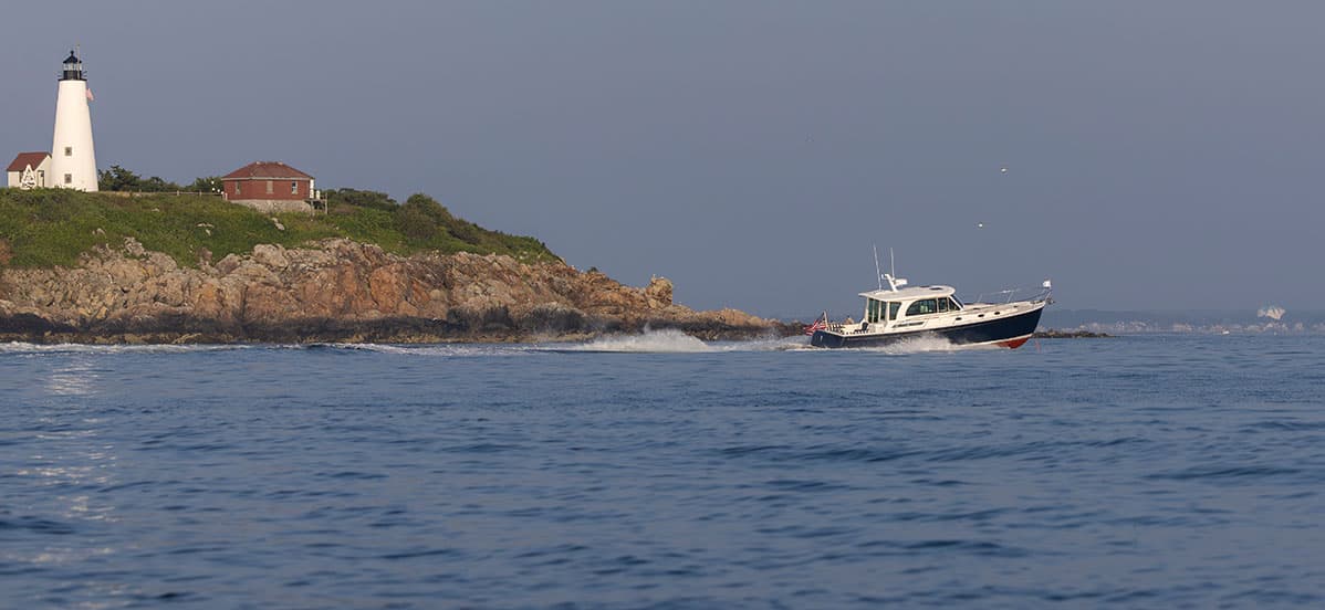 The Back Cove 412 cruising at speed. Maine coast with shore and lighthouse.